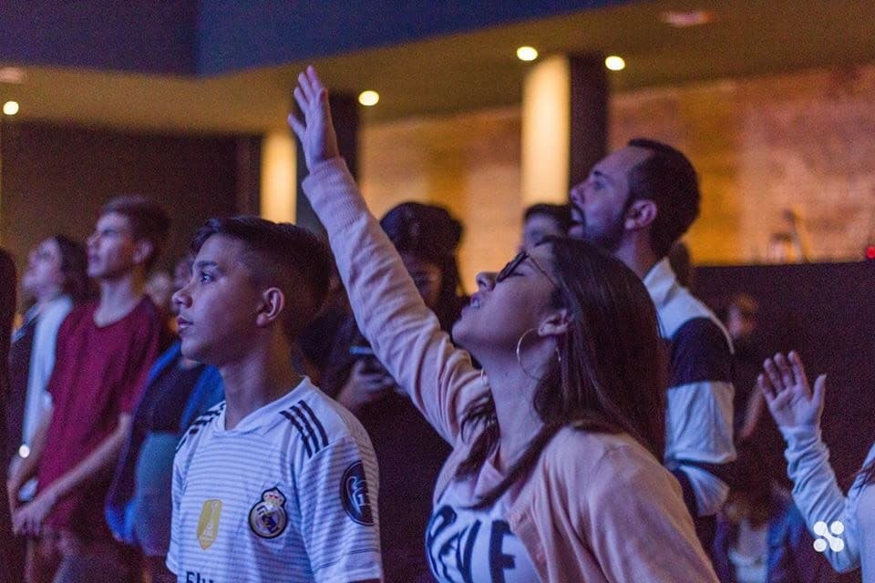 Teenagers worshipping, one girl with her hand raised