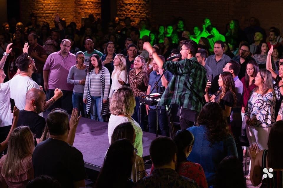 A worship leader singing in the middle of the people, hands raised all around
