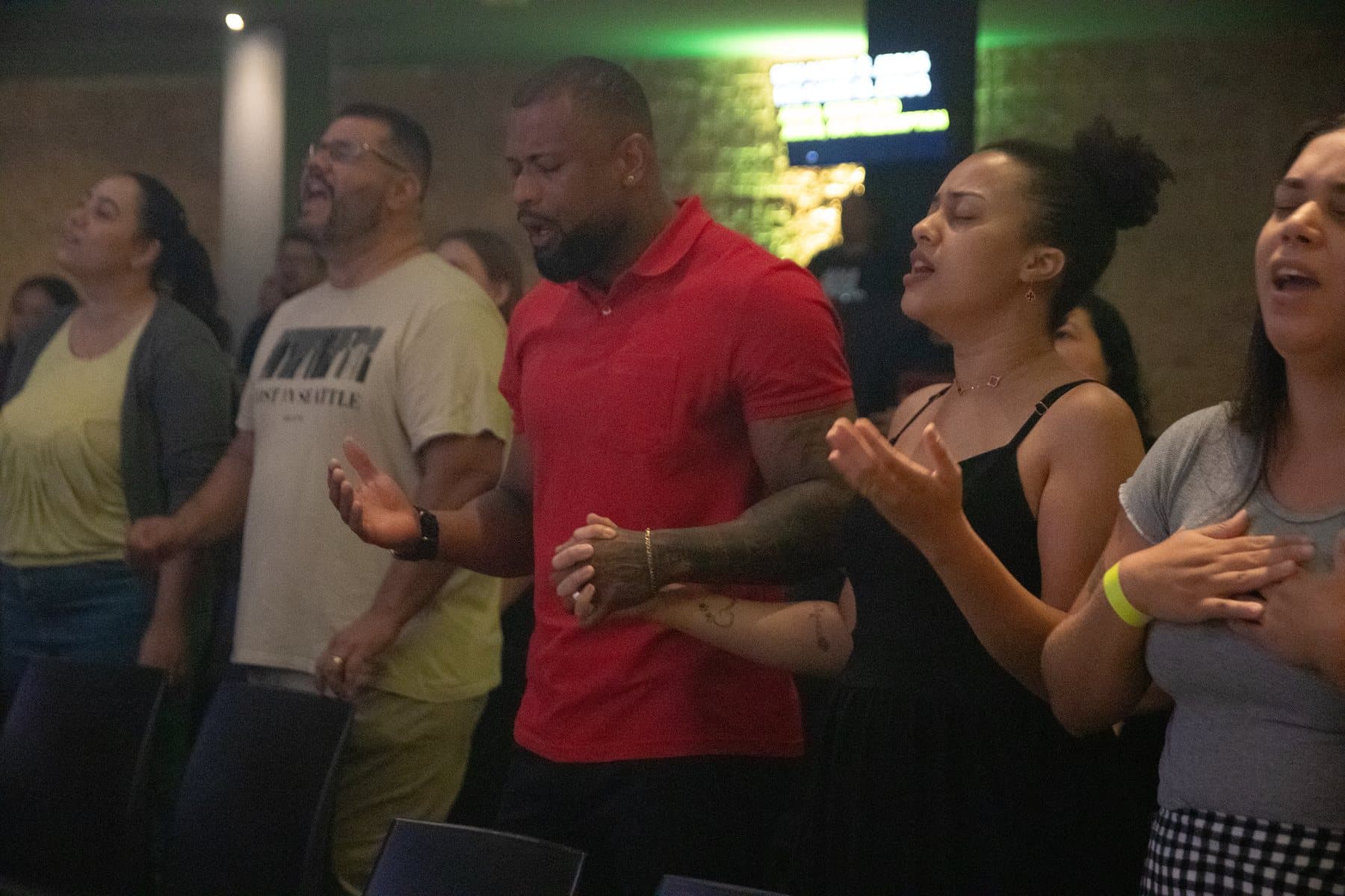 People worshipping during a service, singing with open hands
