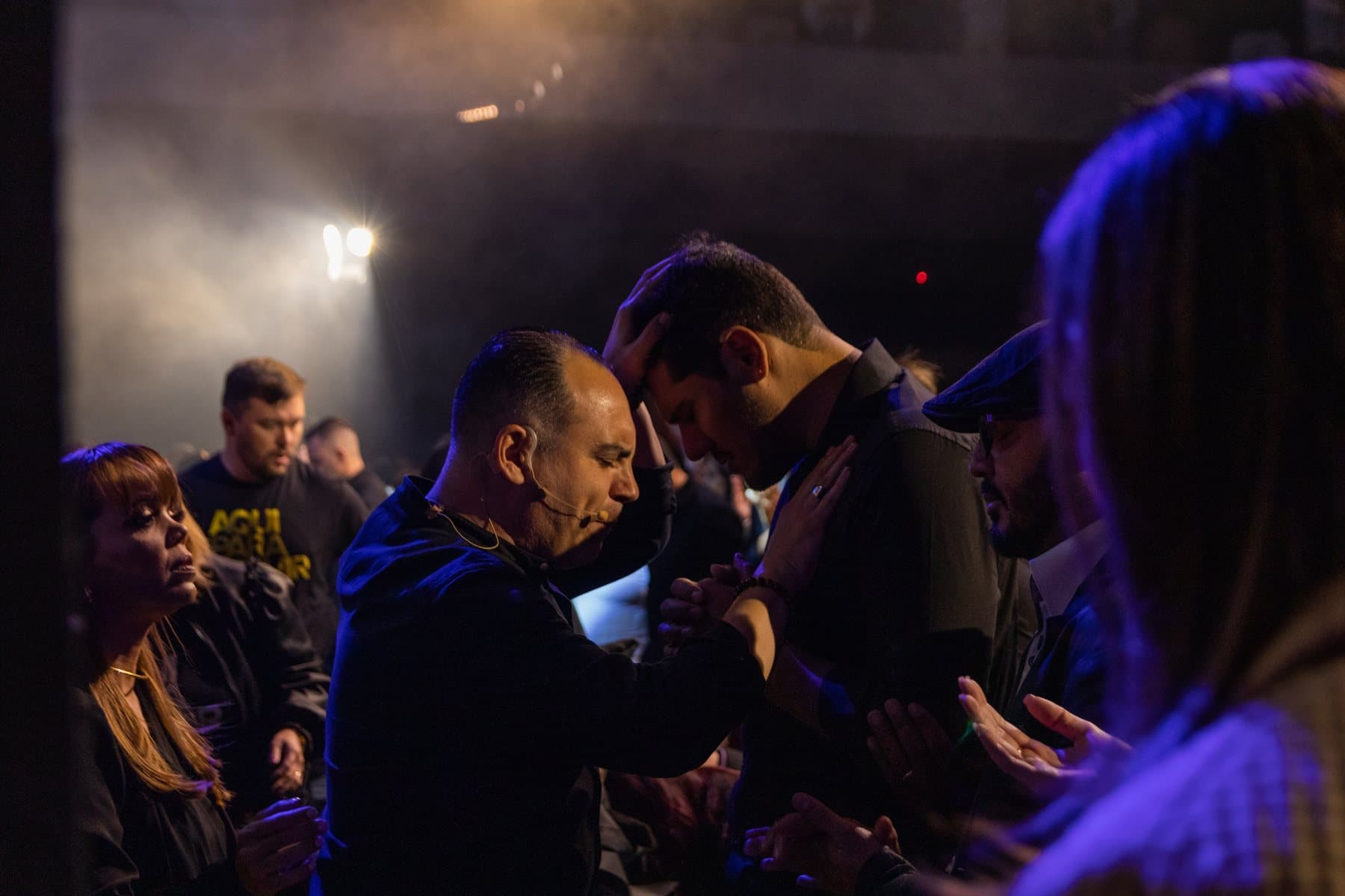Pastor Claudinei praying for a young man during a service